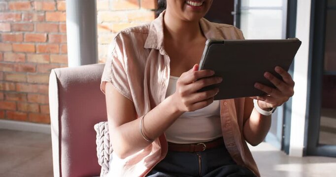 African American women in booth after ping one moving tablet other wearing headset typing on laptop