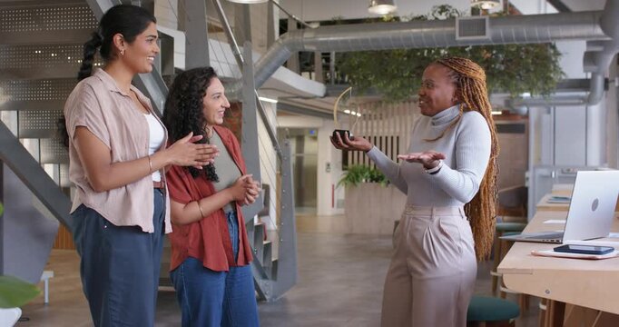 Diverse coworkers celebrating trophy presentation, clapping while recipient raising trophy