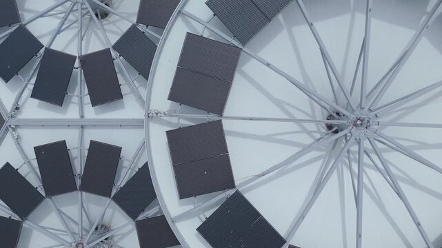 Top down aerial drone footage of a small gas station roof fitted with solar panels. Sustainable energy, clean technology and modern infrastructure viewed from directly above.