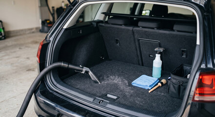 Fototapeta premium Car trunk cargo area with spray bottle, blue cloth, and cleaning items arranged on black carpet for detailing work with professional automotive detailing supplies