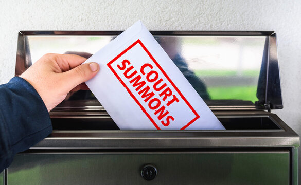 Hand Placing Court Summons Envelope into Mailbox