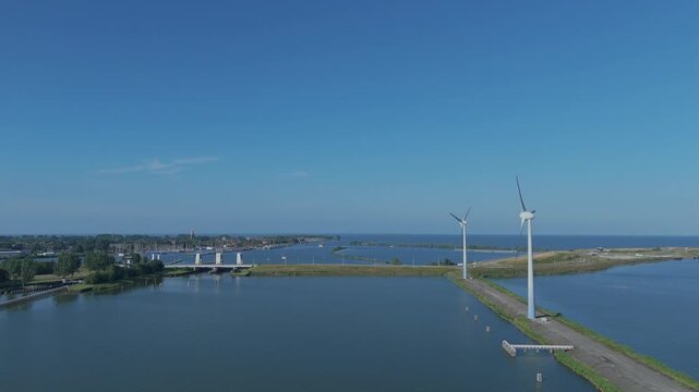 Aerial view flying along a dike near Enkhuizen, with wind turbines in the foreground and Enkhuizen with the IJsselmeer in the background.