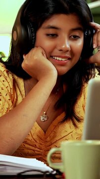 Indian Asian teenage school girl studying online at home using laptop, desktop PC, tablet in a cozy lavish home, focused on education, homework, exam preparation with modern technology in study area