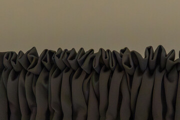 Obraz premium Dark fabric with gathered pleats. Soft folds create textured pattern. Neutral background enhances detail. Ruched design suitable for drapery. Close-up shows material's softness