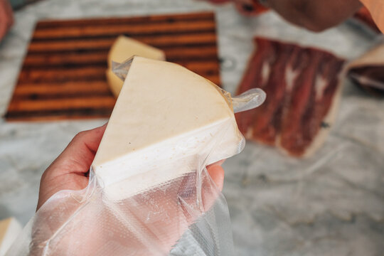 Hand holding a wedge of vacuum sealed cheese, ensuring food preservation and freshness for dairy products