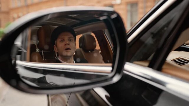 Portrait of middle aged Caucasian chauffeur looking in side mirror with shocked expression. Footage is perfect for car insurance commercials or ridesharing safety campaigns