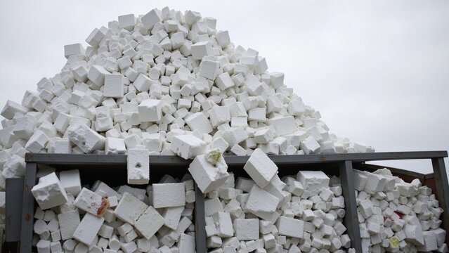 Overfilled Industrial Dumpster Containing Stacked Styrofoam Waste Blocks Under Gray Sky