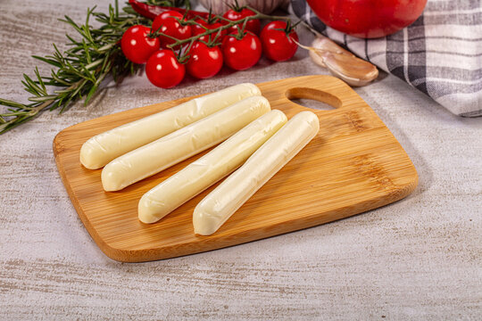 String mozzarella cheese sticks on wooden board with fresh vegetables