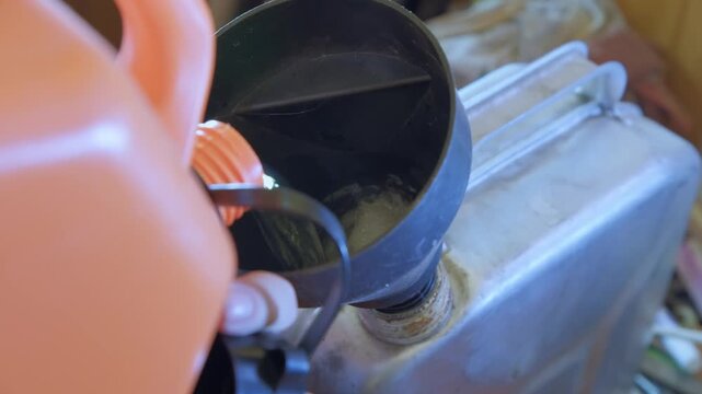 Filling a gas can with fuel while working in a garage on a sunny afternoon
