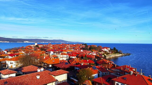 Nessebar town and coastal hills, Bulgaria. Elevated shot overlooking red roofed old town with distant mountains and calm sea horizon.