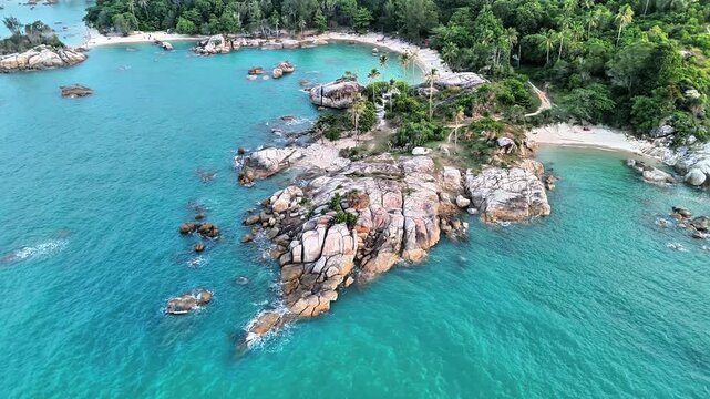 Aerial drone view of Teluk Karang Beach Bangka featuring turquoise tropical waters, granite rock coastline, lush forest and secluded paradise scenery