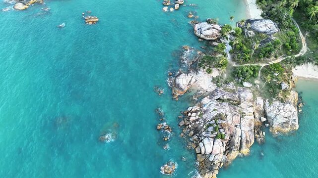 Cinematic aerial drone view of tropical beach with granite coastline, turquoise ocean, hidden coves and untouched island paradise landscape beauty