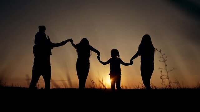 Family silhouette holding hands at sunset with child playing with toy airplane outdoors. Parents and children form chain during golden hour. Families bond together at dusk. Play and unity.