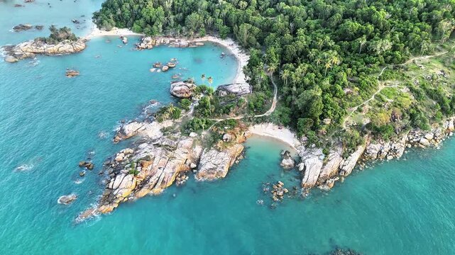 Cinematic aerial drone view of tropical beach featuring granite coastline, turquoise ocean, hidden white sand coves and lush green island scenery