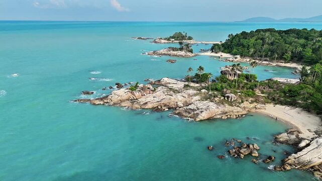 Drone footage capturing granite coastline surrounded by turquoise sea, tropical vegetation, hidden beaches and breathtaking cinematic coastal beauty