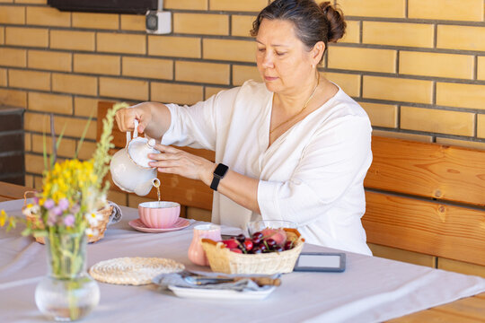 Senior Woman in outdoors gazebo slowly eats  breakfast alone. Slow lifestyle concept
