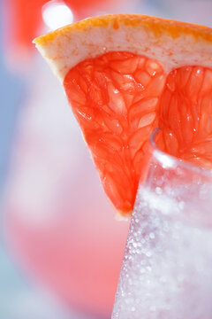 Close-up of a refreshing pink grapefruit cocktail with ice, fresh rosemary, and a juicy grapefruit wedge garnish.Vibrant macro food photography, restaurant menus, cocktail bars, healthy beverages
