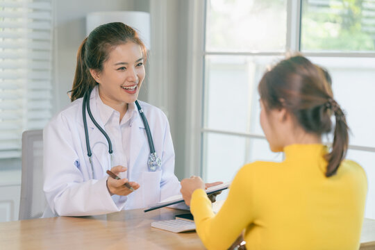 Professional woman physician talking and giving advice to female patient at clinic desk