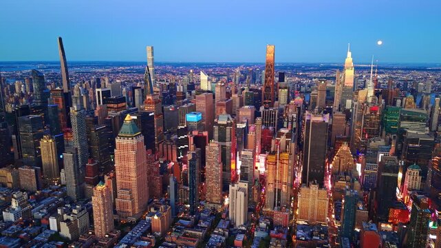 Elevated skyline of Manhattan at blue hour, New York. Illuminated skyscraper, avenue traffic and distant river under clear sky.