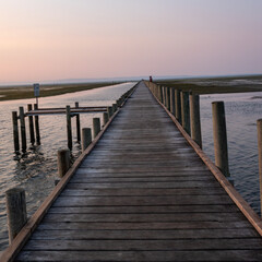 Fototapeta premium Wooden boardwalk leading through the Grado Lagoon at sunset, Grado, Italy