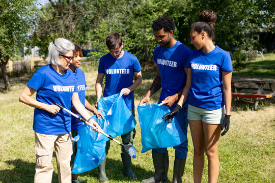 Diverse volunteers cleaning up park with trash bags