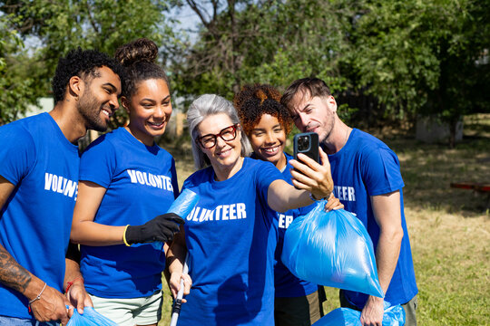 Diverse volunteer team taking selfie after cleaning park