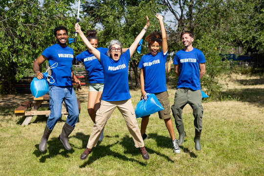 Diverse volunteers jumping celebrating successful community cleanup