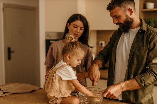 Family cooking together, parents teaching daughter in kitchen