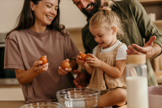 Family cooking together in kitchen making breakfast eggs