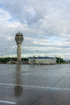 Airport control tower behind a rain covered terminal window