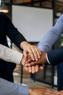 Diverse Team Stacking Hands Together in Unity at Modern Office Meeting Room Showing Teamwork and Collaboration