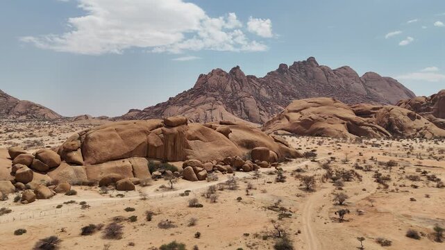 Cinematic aerial footage of the majestic Spitzkoppe granite peaks in Namibia. Massive rock formations dot the dry desert savanna in this wild African environment.