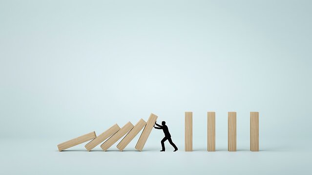 A man stops a falling row of wooden blocks from hitting a standing row.