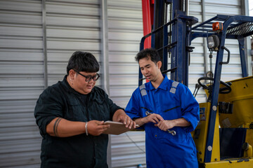 Mechanics collaborating on forklift inspection and maintenance planning © Wasana