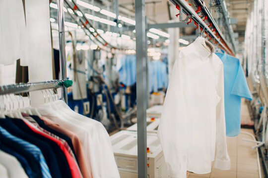 Dry cleaning clothes. Clean cloth chemical process. Laundry industrial dry-cleaning. Clean clothes and snow-white shirts are hanging on hangers conveyor belt and ready for delivery to the client.