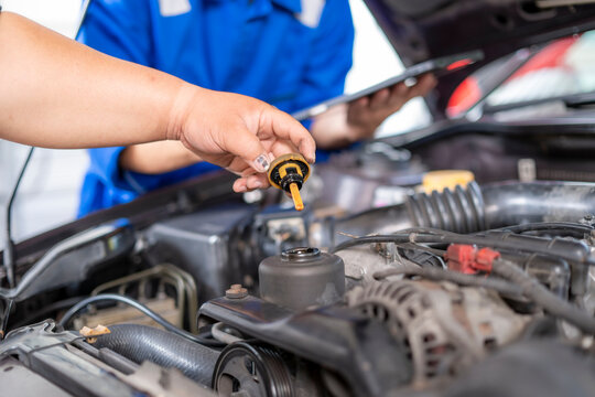 Hand checking engine oil dipstick during car service
