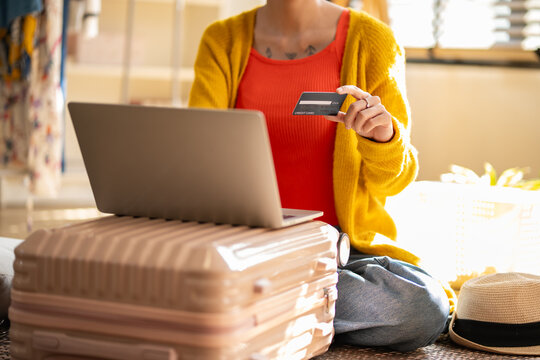 Asian woman using credit card for online hotel booking platform on laptop, representing creative professional women travel payment transaction, e-commerce shopping and holiday planning