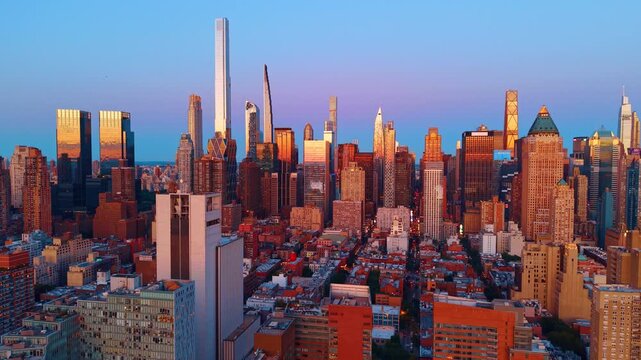 Midtown Manhattan skyline under clear evening sky. Skyscrapers and residential blocks reflect warm sunset light in New York City.