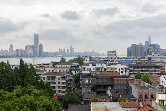 Wuhan city, the capital of Hubei, China. An urban river cityscape showing older residential buildings in the foreground and a distant modern skyline across the water under a cloudy sky