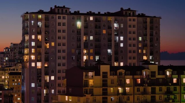 Timelapse: view of panel apartment building in Batumi. Blinking windows in typical georgian residential buildings with warm illumination light from dusk to night. Architecture and time lapse concept