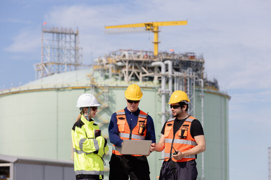 Engineers and construction workers collaborating on a project at a modern industrial site with machinery in the background