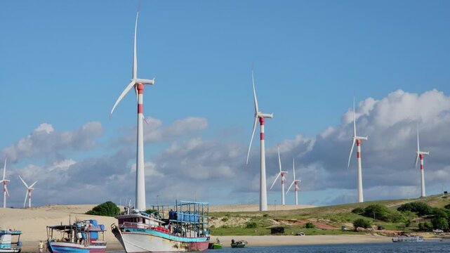Coastal community and green technology: Traditional fishing vessels on Munda&uacute; river with a background wind farm