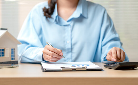 Front view and close up hand of woman point to calculator on table during work with writing on data paper.