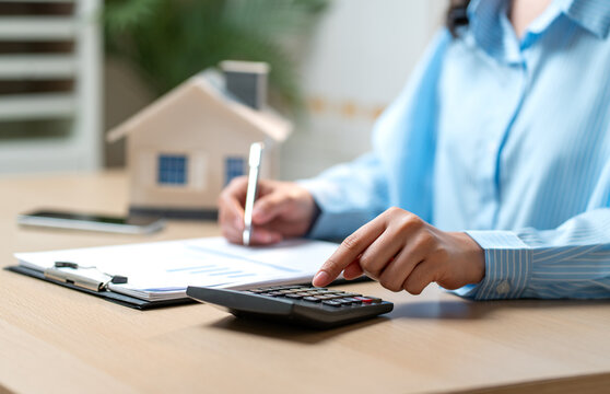 Close up hand of woman point to calculator on table during work with writing on data paper.