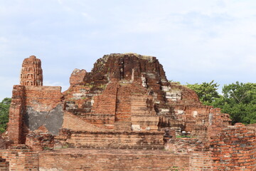Fototapeta premium Ancient Ruins of Ayutthaya: Weathered brick structures and crumbling stone edifices stand testament to the passage of time, evoking a sense of historical grandeur and mystery amidst lush greenery.