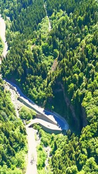 Vertical video. Altindere, Trabzon Province, Turkey. Sumela Monastery, a Greek Orthodox complex clinging to a sheer cliff face above dense coniferous forest, aerial view over the winding Altindere Va