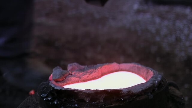 Close Up Of Foundry Worker Adding Flux Powder To Molten Bronze Inside Traditional Foundry - 4K