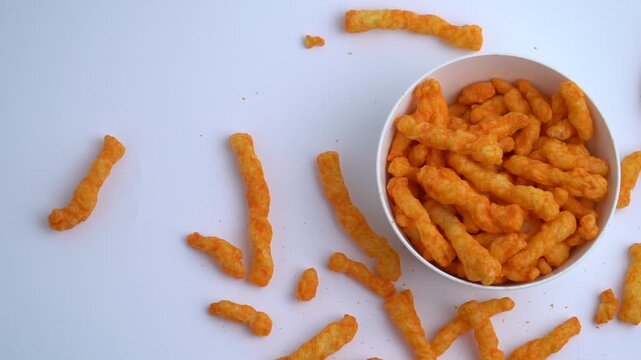 Flat lay Puff corn cheese in a white plastic bowl and the surrounding area isolated on a white background