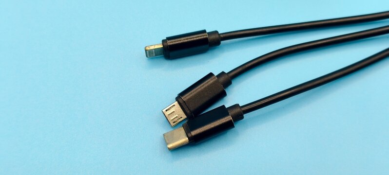 Close‑up of three black charging cables with different connectors on a light blue background. The set includes a Lightning connector, a Micro‑USB connector , and a modern USB Type C.