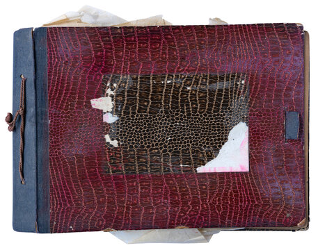 Vintage worn photo album with torn red leather cover and old papers on white